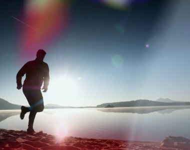 Kaçak ışık objektif. Adam siluet sabah güneş karşı sahilde egzersiz.