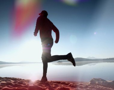 Kaçak ışık objektif. . Çalışan adam. Koş, sporcu adam kumlu bir plaj üzerinde gündoğumu sırasında koşu.