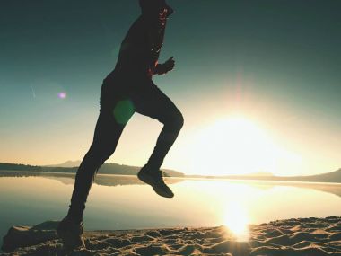 Gün doğumunda yansımayla plajda koşan bir çocuk. Açık gökyüzü ile Sabah Koyu Sahili.