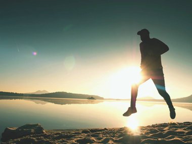 Güzel bir gün batımı fon karşı sahilde koşan adam. Kum dağ gölü
