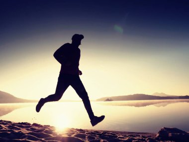 Uzun kumsalda hızlı deniz kıyısında koşan adam uygun. Güçlü runner yaz sabah açık eğitim.