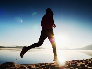 Uzun kumsalda hızlı deniz kıyısında koşan adam uygun. Güçlü runner yaz sabah açık eğitim.