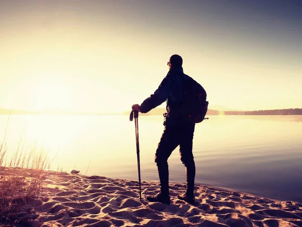 Hombre turista con una mochila y bastones de trekking de pie en la playa de arena. Senderista disfrutar — Foto de Stock