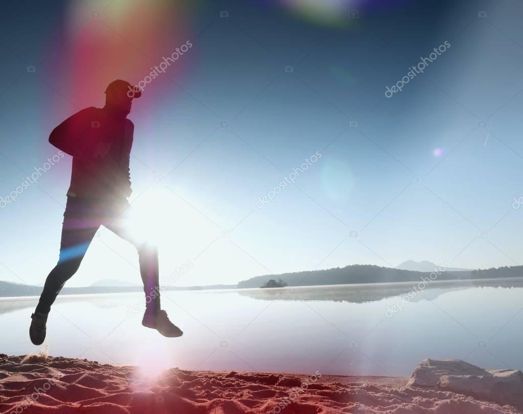 Leakage of light in the lens. . Running man. Sportsman run, jogging guy during the sunrise above sandy beach.