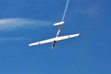 Memorial Airshow. Flying Glider aerobatic team withlight sailplane showing his performance, smoke effect clipart