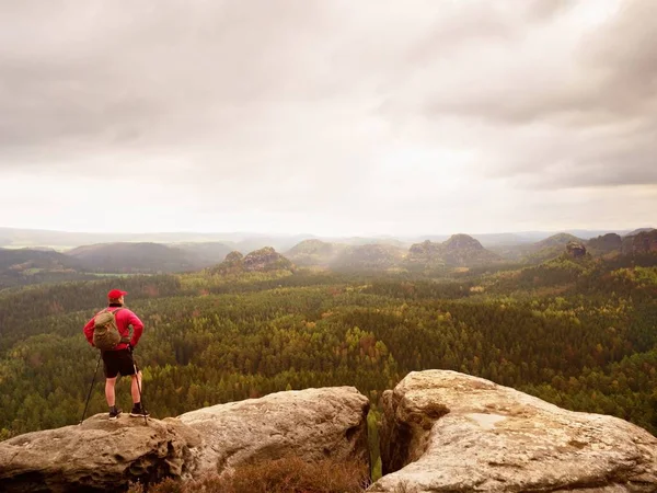 Guida turistica su punto di vista roccioso con pali in mano. Escursionista con zaino sportivo stand su roccia — Foto Stock