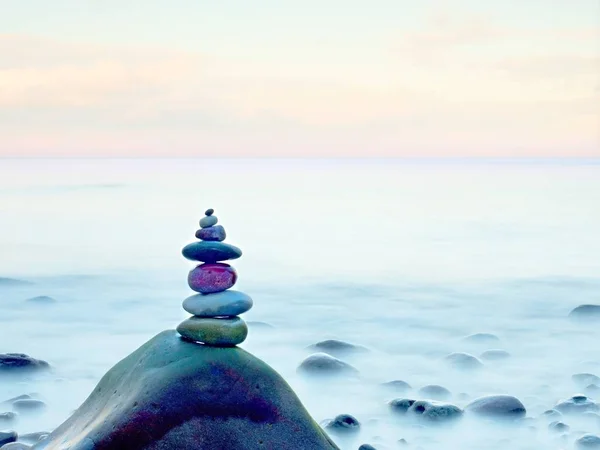 Balanserad sten pyramide på stranden av blått vatten i havet. Blå himmel i vattennivån spegel — Stockfoto