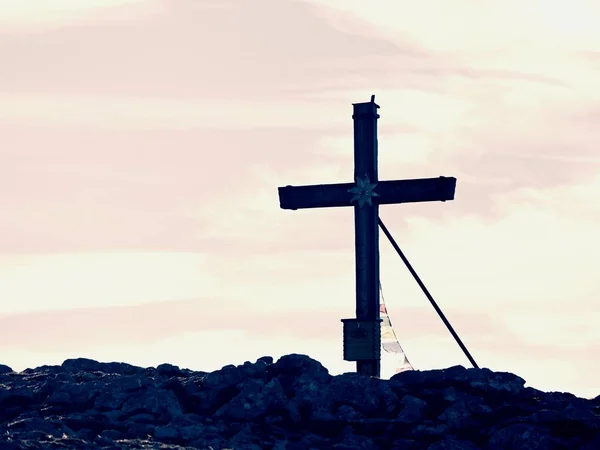 Großes Kreuz auf dem Gipfel des Berges, wie es typisch für die Alpen ist. Holzkreuz mit buddhistischen Gebetsfahnen — Stockfoto