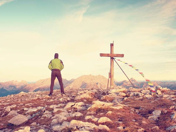 Alone man climber near the summit cross on peak, Dolomite Alps, Austria. Sunny windy evening. — Stock Photo, Image