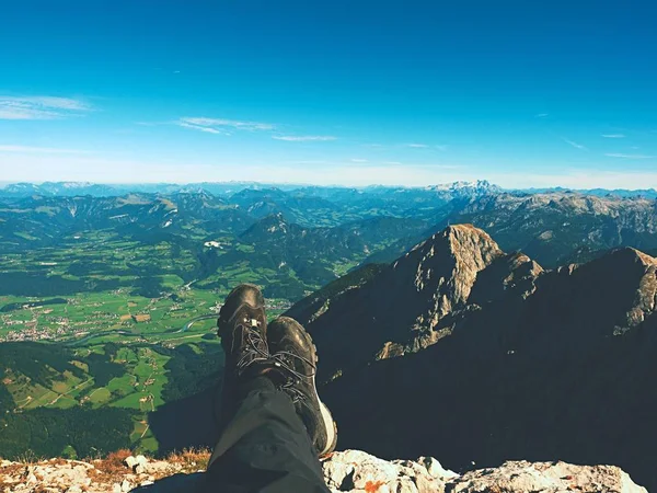 Vista em primeira pessoa para o corpo e paisagem distante. Homem pernas ter um descanso no topo da montanha . — Fotografia de Stock