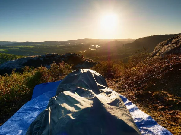 Beautiful awakening in a sleeping bag on  rock ledge. Birds are singing and Sun at horizon. — Stock Photo, Image