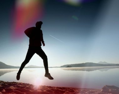  egzersiz ve göl kumsalda güneş doğarken uzanan bir adam. Sağlıklı bir yaşam tarzı. Yalnız genç fitness adam egzersiz sabah kumsalda