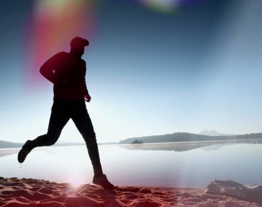 Gündoğumu kıyıda çalışan etkin atlet runner silüeti. Sabah sağlıklı yaşam tarzı egzersiz