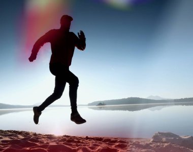 Kaçak ışık objektif. . Çalışan adam. Koş, sporcu adam kumlu bir plaj üzerinde gündoğumu sırasında koşu.