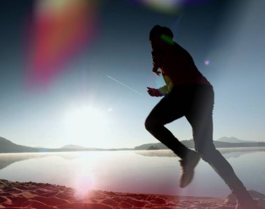 Kaçak ışık objektif. Adam siluet sabah güneş karşı sahilde egzersiz.