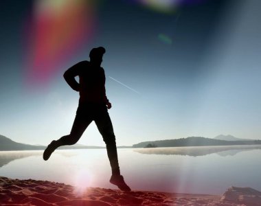 Kaçak ışık objektif. Adam siluet sabah güneş karşı sahilde egzersiz.