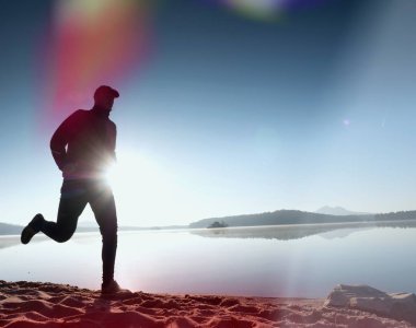 Kaçak ışık objektif. . Çalışan adam. Koş, sporcu adam kumlu bir plaj üzerinde gündoğumu sırasında koşu.