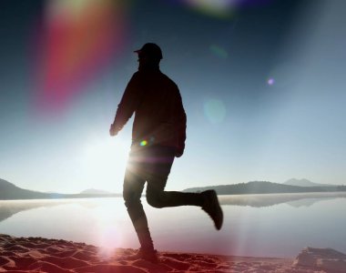 Kaçak ışık objektif. Adam siluet sabah güneş karşı sahilde egzersiz.