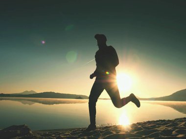 Gün doğumunda yansımayla plajda koşan bir çocuk. Açık gökyüzü ile Sabah Koyu Sahili.