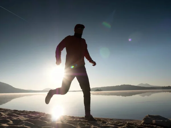 남자 비치는 아름 다운 일몰의 배경에서 실행. 산 호수의 모래 — 스톡 사진