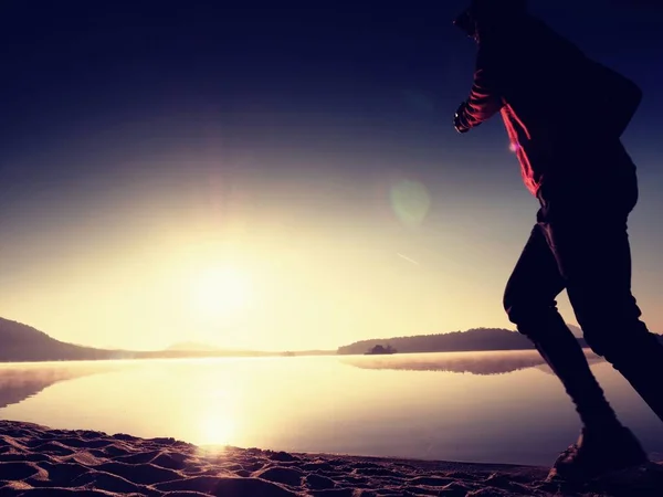 Man loopt op strand tegen de achtergrond van een prachtige zonsondergang. Zand van bergmeer — Stockfoto
