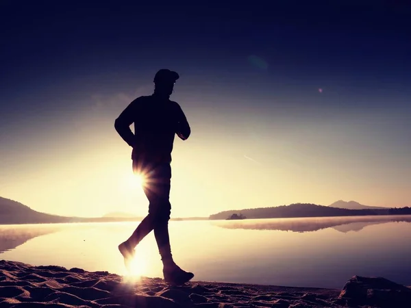 Człowiek działa na plaży na tle pięknego zachodu słońca. Piasek z góry jezioro — Zdjęcie stockowe