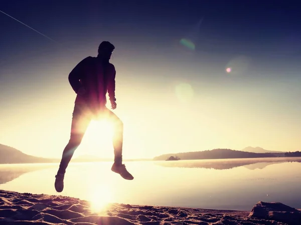 Homem correndo na praia contra o pano de fundo de um belo pôr do sol. Areia de lago montês — Fotografia de Stock