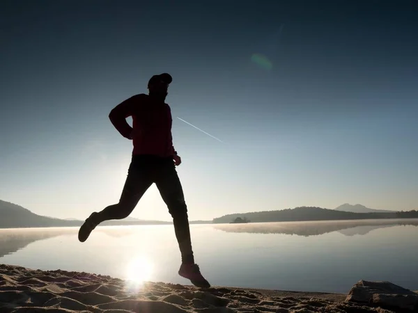 Hombre alto en forma corriendo rápido por el mar en la playa. Potente entrenamiento de corredor al aire libre en la mañana de verano . — Foto de Stock