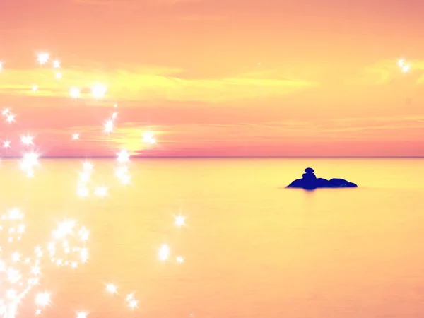 Film hatása. Romantikus reggel a tengeren. Nagy sziklák kilóg a sima hullámzó tenger. Az első meleg nap sugarai rózsaszín horizon. — Stock Fotó
