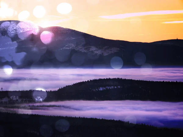 Эффект фильма. Розовое оранжевое солнце поднимается над туманными зимними горами, сияя туманом. Вершины гор над сливочным туманом в долине . — стоковое фото