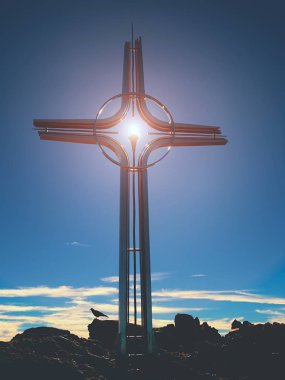 Yüksek kayalık dağ Shinning çarmıhta. Çelik sanatsal haç Alp dağın zirvesinde,