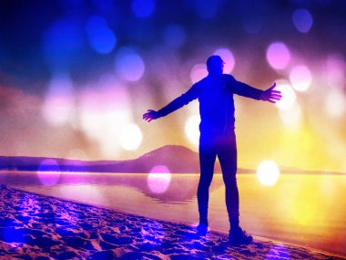 Film etkisi. Adam sahilde egzersiz. Egzersiz ve göl kumsalda güneş doğarken germe etkin adam silüeti.