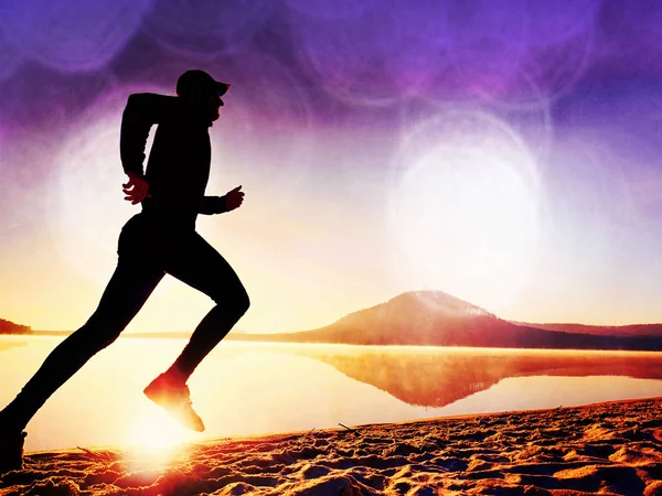 Film effect. Sportsman  running at amazing summer sunset along coastline in sport and healthy lifestyle concept