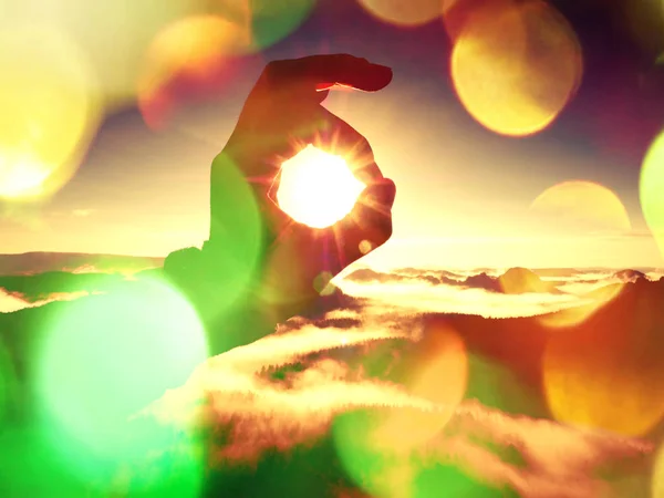 Efecto de película. La mano del hombre toca Sun. Amanecer brumoso en una hermosa colina. Picos de colinas sobresalen de la niebla — Foto de Stock