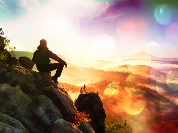 Efecto de la película.Hombre excursionista tomar un descanso en la cima de la montaña. El hombre yacía en la cima, bajo el valle del otoño. Sol de la mañana brillante — Foto de Stock