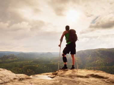 Adam bir koltuk değneği ile ve kırık bacak koltuk değneği üzerinde sabit. Gezgin bandaj yaralı bacak ile kal devam et