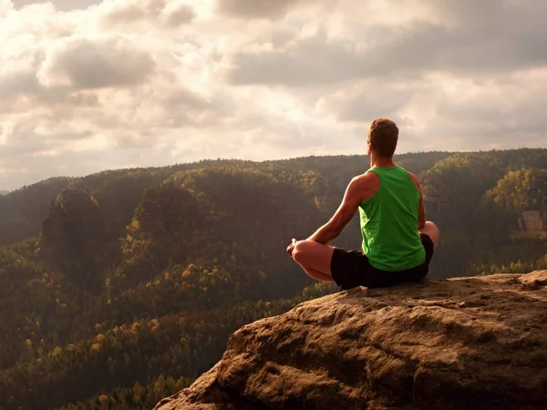 Hombre en la cima de la montaña en pose de yoga. Ejercicio yoga en el borde con una vista impresionante —  Fotos de Stock