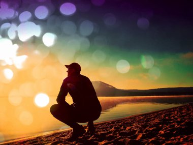 Film etkisi. Adam sahilde egzersiz. Egzersiz ve göl kumsalda güneş doğarken germe etkin adam silüeti.