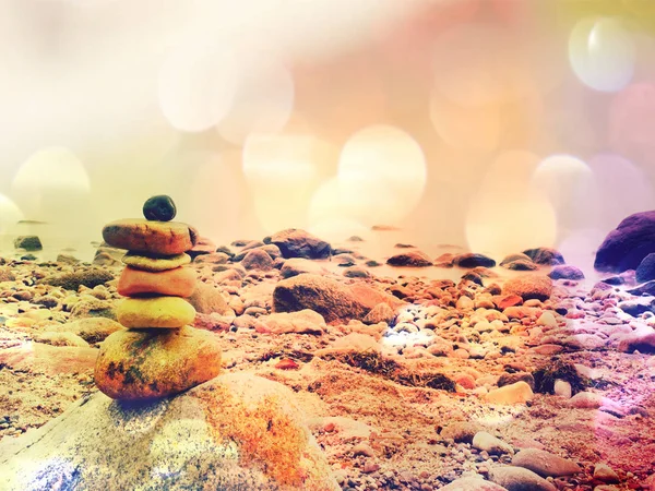 Efeito de filme. Pirâmide de pedra equilibrada na costa do mar, ondas no fundo. Pedras planas coloridas para meditação deitada no mar — Fotografia de Stock