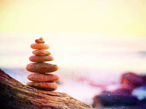 Grano de película. Pirámide de piedra equilibrada en la orilla del mar, olas en el fondo —  Fotos de Stock