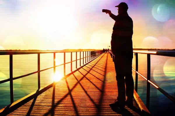 Film grain. Man on pier photograph morning sea. Tourist with smart phone in hand. Fantastic morning with  smooth water level