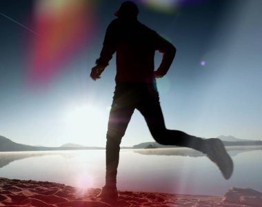  egzersiz ve göl kumsalda güneş doğarken uzanan bir adam. Sağlıklı bir yaşam tarzı. Yalnız genç fitness adam egzersiz sabah kumsalda