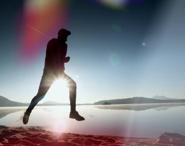  egzersiz ve göl kumsalda güneş doğarken uzanan bir adam. Sağlıklı bir yaşam tarzı. Yalnız genç fitness adam egzersiz sabah kumsalda