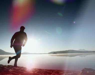  egzersiz ve göl kumsalda güneş doğarken uzanan bir adam. Sağlıklı bir yaşam tarzı. Yalnız genç fitness adam egzersiz sabah kumsalda