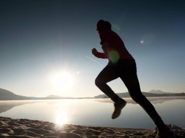 Güzel bir gün batımı fon karşı sahilde koşan adam. Kum dağ gölü