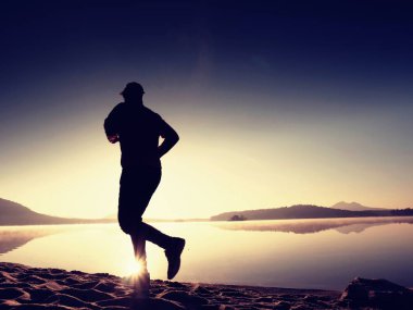 Uzun kumsalda hızlı deniz kıyısında koşan adam uygun. Güçlü runner yaz sabah açık eğitim.