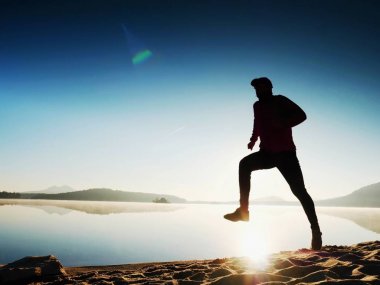 Gün doğumunda yansımayla plajda koşan bir çocuk. Açık gökyüzü ile Sabah Koyu Sahili.