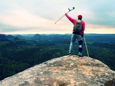 Tepe zafer. Adam bacak diz kafesleri ve istikrar ve yürüme destek için koltuk değneği ile.