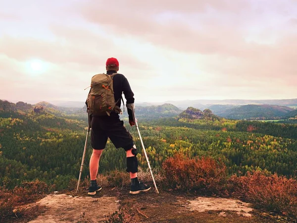 Hombre excursionista con corsé de pierna de apoyo y engullir las cruces. Parque forestal natural —  Fotos de Stock