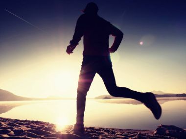 Gün doğumunda yansımayla plajda koşan bir çocuk. Açık gökyüzü ile Sabah Koyu Sahili.